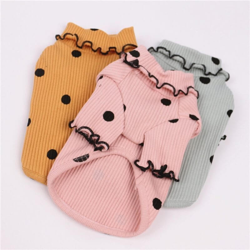 Three ribbed dog sweaters in yellow, pink, and gray with black polka dots on a white background.