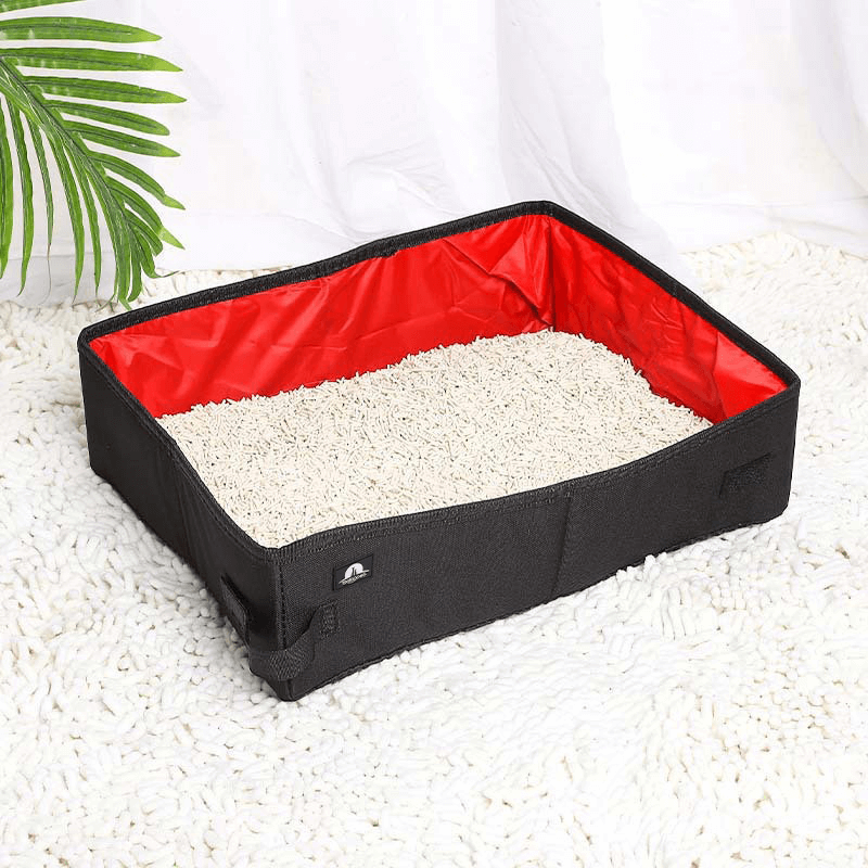 Portable foldable cat litter box with red waterproof interior and black Oxford cloth exterior, filled with litter and placed on a white rug—ideal for travel and home use.