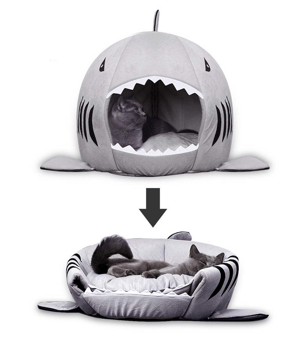 Two-in-one pet bed in shark shape shown in upright cave mode and flattened into an open cushion, featuring a relaxed gray cat lounging inside.