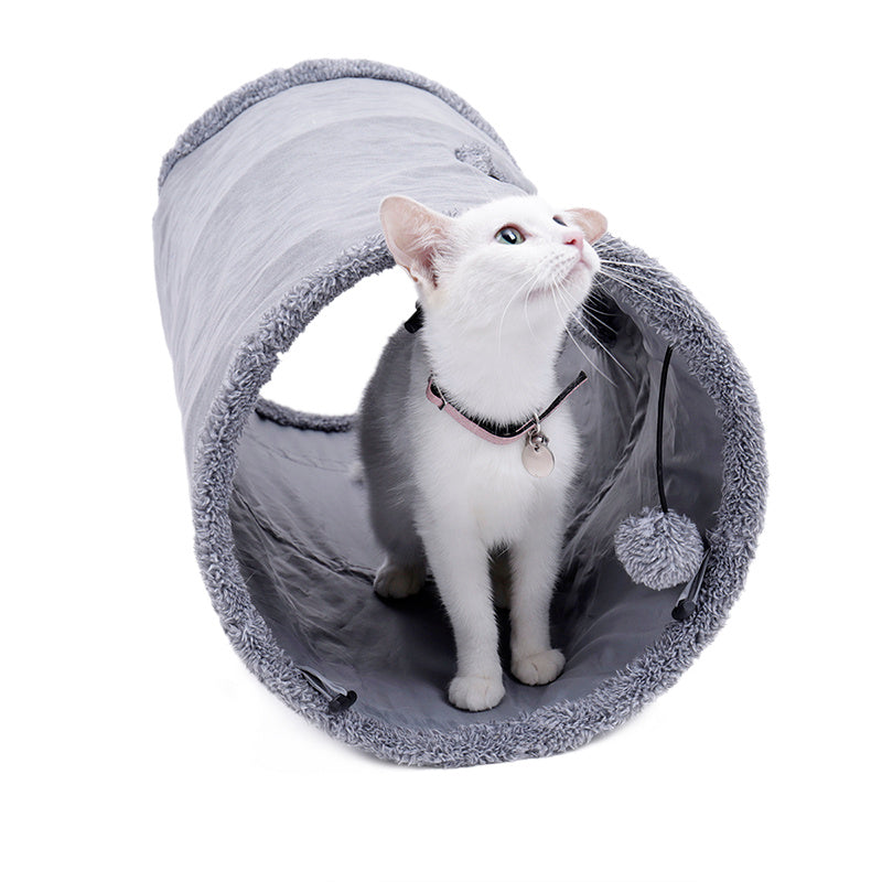 Curious kitten peeking out from a cozy grey play tunnel, enjoying an interactive toy.