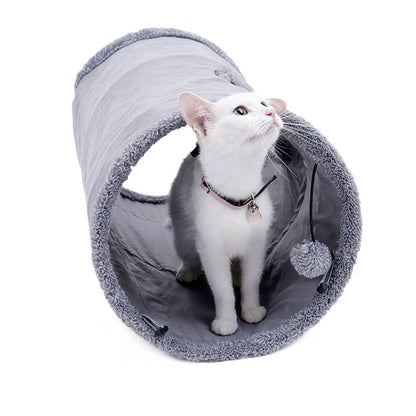 Curious kitten peeking out from a cozy grey play tunnel, enjoying an interactive toy.