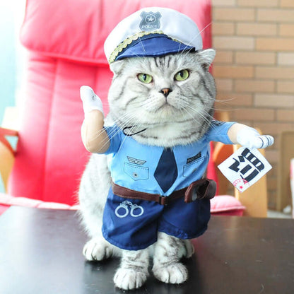 Cat wearing a police costume with a hat and uniform on a table.