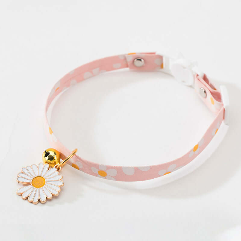 Pink polka dot choker with a white daisy charm on a light gray background