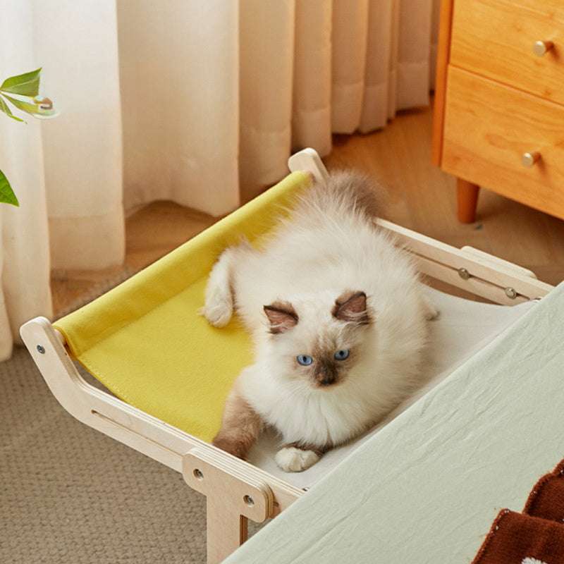 Indoor pet hammock with wooden frame and relaxed cat lying on top.
