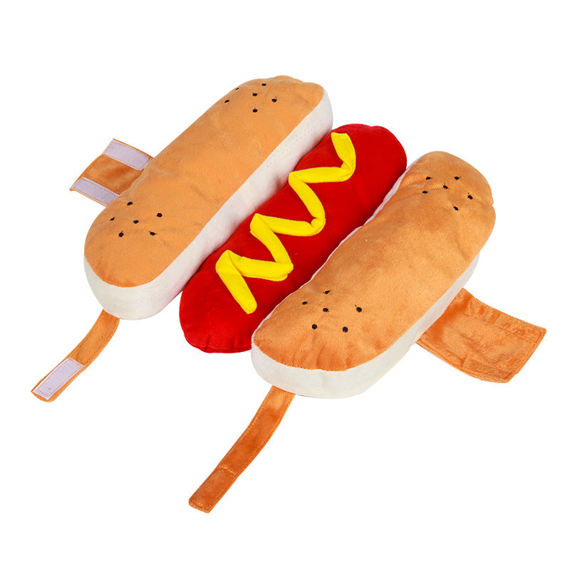 Plush toy shaped like a hot dog with bun, red body, and yellow mustard on a white background