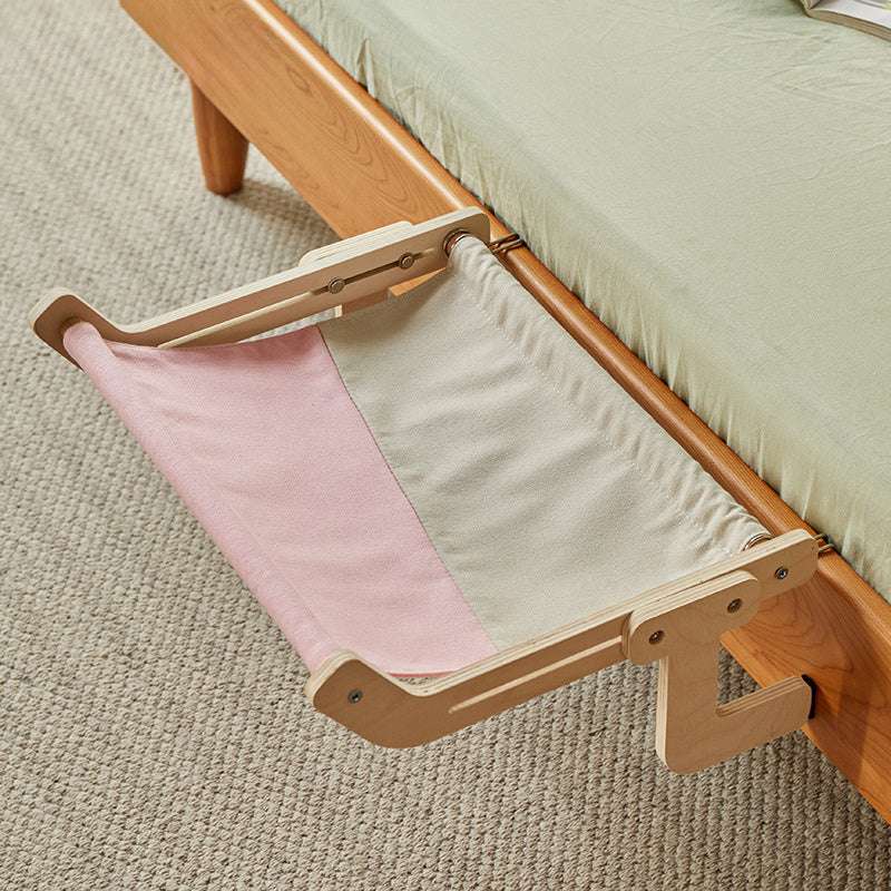 Cute kitten resting peacefully on a suspended hammock next to the bed.