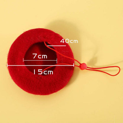 Close-up of a red velvet bow with gold bell detail, designed for cats, shown next to a matching beret.