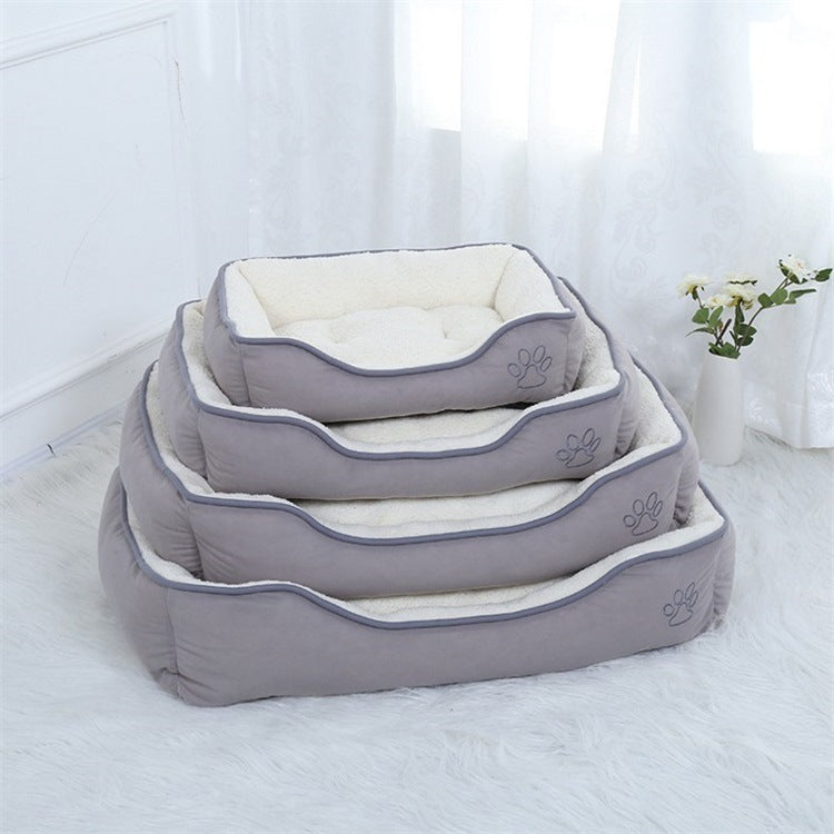 Cozy white pet bed with soft plush interior, placed on a fluffy carpet beside a vase of flowers.
